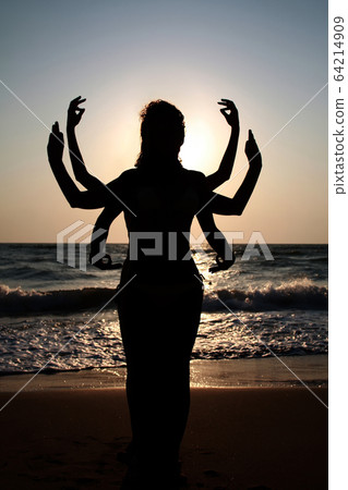 Girls silhouettes standing at the beach with arms raised up. Yog Girls silhouettes standing at the beach with arms raised up. Yog 64214909