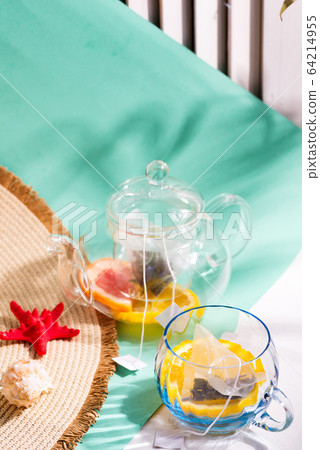 Summer layout from wide-brimmed hat and glass set with ingredients for making fresh fruit cold tea drink on a duotone pastel background. Summer layout from wide-brimmed hat and glass set with ingredients for making fresh fruit cold tea drink on a duotone pastel background. 64214955