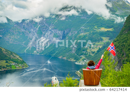 Tourist over Geirangerfjord holds norwegian flag 64217414