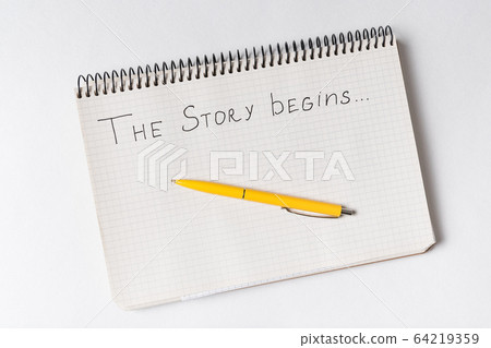 Notepad with words THE STORY BEGINS. Top view of Notepad with words THE STORY BEGINS. Top view of 64219359