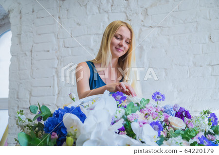 Florist making large floral basket with flowers at flower shop Florist making large floral basket with flowers at flower shop 64220179