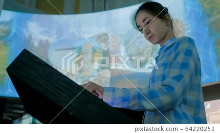 Woman using interactive touchscreen display at modern history museum Woman using interactive touchscreen display at modern history museum 64220251