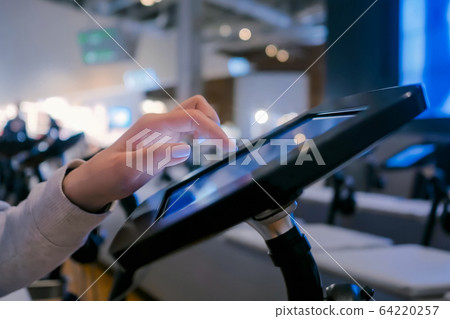 Woman hand using touchscreen display of floor standing black tablet kiosk Woman hand using touchscreen display of floor standing black tablet kiosk 64220257