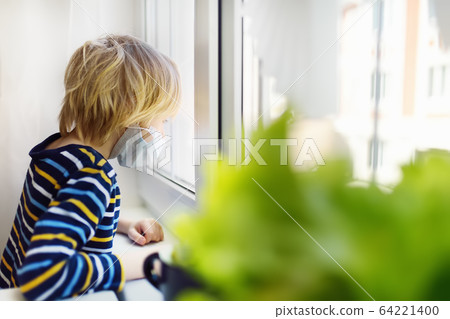 Sad little boy looking into window  64221400