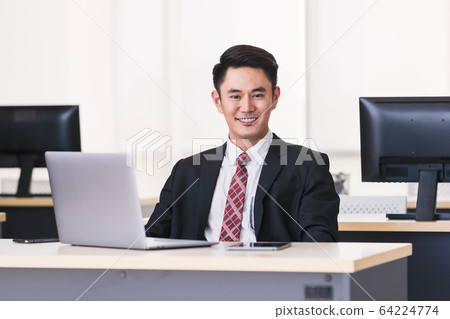 Asian businessman smiling and sittting in office,. 64224774
