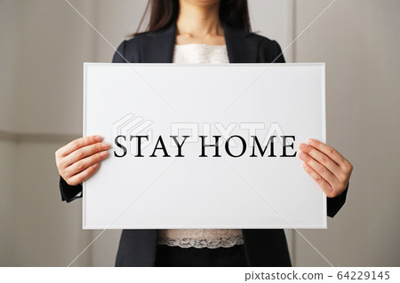 A woman with a whiteboard that says stay home 64229145