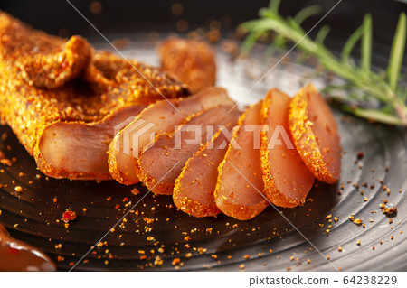 Seasoned chicken with hot sauce and a sprig of rosemary 64238229