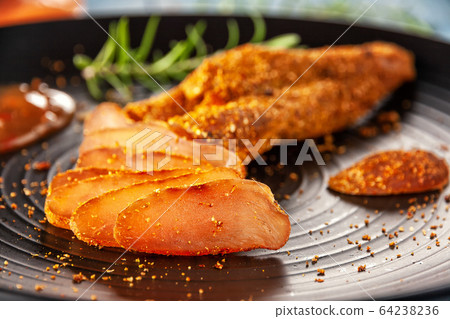 Seasoned chicken with hot sauce and a sprig of rosemary 64238236