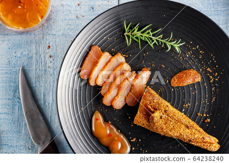 Seasoned chicken with hot sauce and a sprig of rosemary 64238240