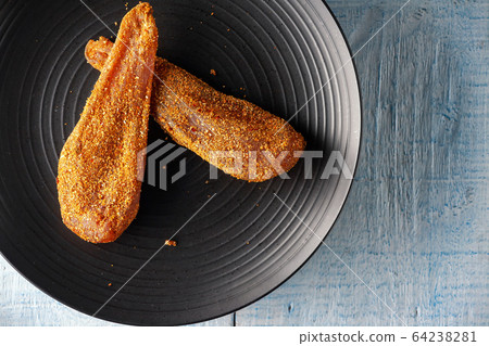 Seasoned chicken with hot sauce and a sprig of rosemary 64238281