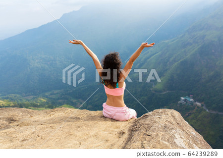 Girl enjoys a mountain view while standing on a Girl enjoys a mountain view while standing on a 64239289