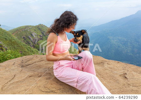 A girl with a dog enjoying the mountain scenery on A girl with a dog enjoying the mountain scenery on 64239290