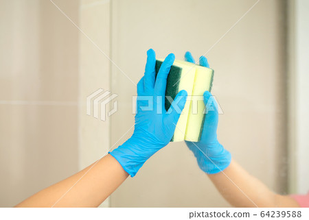 Women hand in a blue rubber glove in the picture, removes and washes bathroom sink by spray and sponge, hygiene concept 64239588