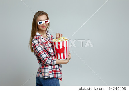 smiling woman in red-blue 3d glasses holding popcorn bucket 64240408