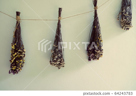bouquet of dried flowers hanging on rope against 64243783