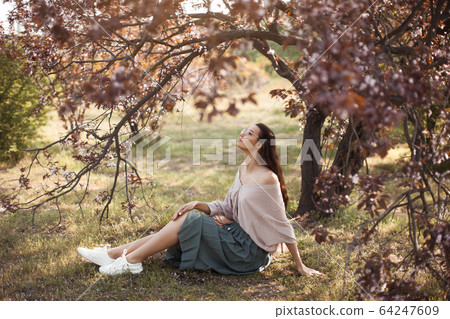 Woman Outdoors in Park Near Spring Blossom Tree Woman Outdoors in Park Near Spring Blossom Tree 64247609