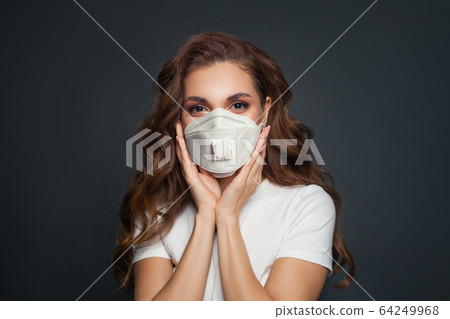 Young woman in face mask on dark gray background. 64249968