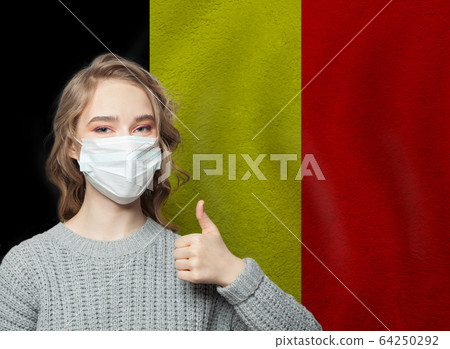 Happy woman in face mask holding thumb up  64250292