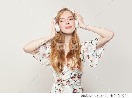 Happy redhead woman with headphones on white Happy redhead woman with headphones on white 64251041