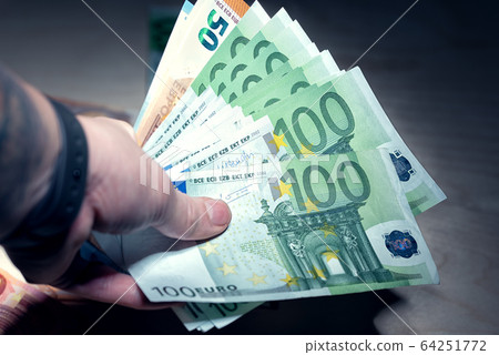 Heap of hundred euro banknotes in the hand Heap of hundred euro banknotes in the hand 64251772