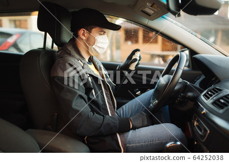Man in car put on black gloves and medical mask to protect himself 64252038