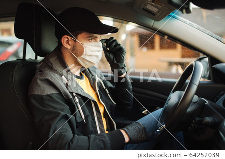 Man in car put on black gloves and medical mask to protect himself Man in car put on black gloves and medical mask to protect himself 64252039