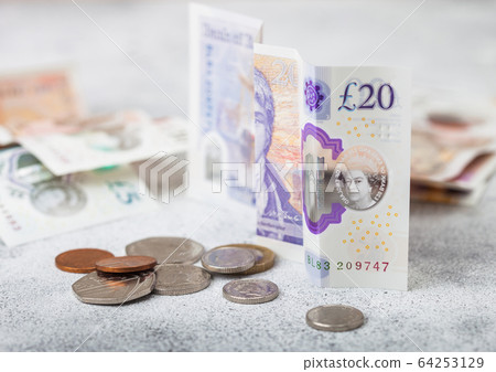 Twenty pounds banknote with coin on light Twenty pounds banknote with coin on light 64253129