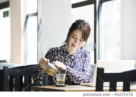 A young woman poured herbal tea 64255378