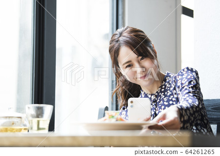 Young woman taking a picture of cooking with a smartphone 64261265