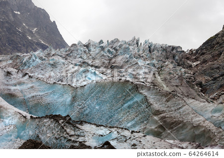 Glacier with deep crevasses covered with snow and 64264614