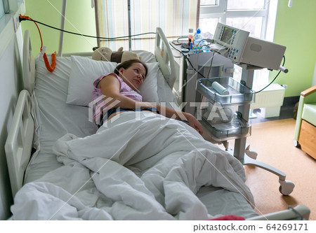 Pregnant woman feels hard contraction in a hospital labor delivery room. Concept photo of pregnancy, pregnant woman, newborn and baby. 64269171