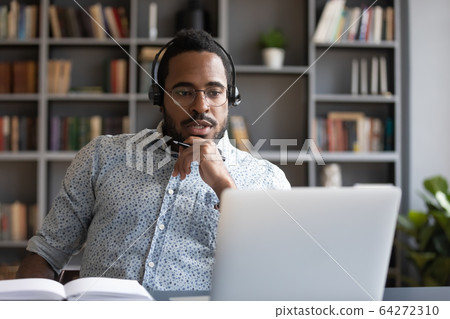 Focused millennial mixed race guy consulting clients online. Focused millennial mixed race guy consulting clients online. 64272310