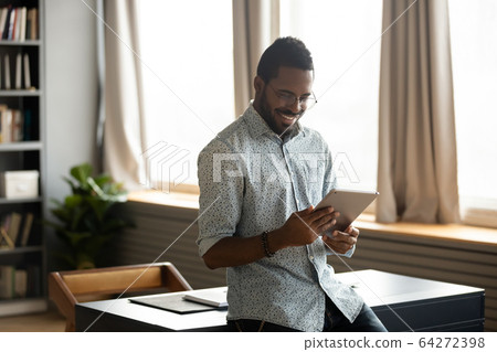 Smiling businessman web surfing information at home on digital tablet. Smiling businessman web surfing information at home on digital tablet. 64272398