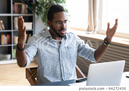 Frustrated young biracial man feeling shocked about online news. Frustrated young biracial man feeling shocked about online news. 64272430
