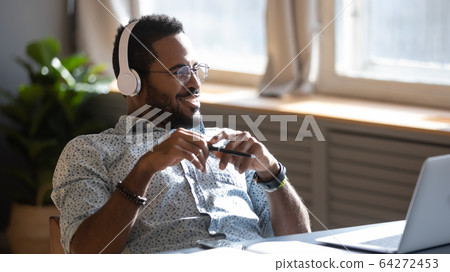 Distracted from job study happy biracial man listening to music. Distracted from job study happy biracial man listening to music. 64272453