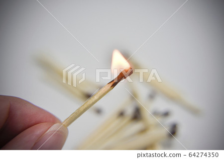 Burning wooden match in the hand with matches on 64274350