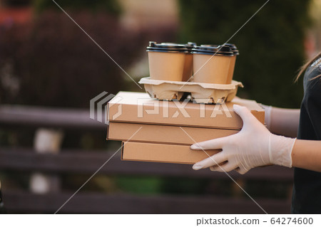 Closeup of courier give order to customer. Man from delivery service bring pizza and coffee. Hands in protective mask Closeup of courier give order to customer. Man from delivery service bring pizza and coffee. Hands in protective mask 64274600