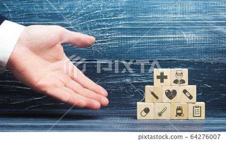 A man presents blocks with medical attributes. Healthcare and medical Insurance concept. Providing hospitals and medical facilities with necessary supplies to curb growth of the coronavirus pandemic 64276007