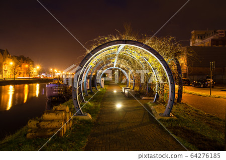 Night view of the cityscape of Bruges, Belgium Cobblestone sidewalk and illuminated tunnel built along the river 64276185