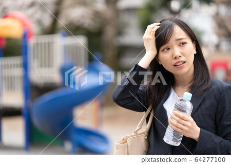 Young woman with plastic bottle in park 64277100
