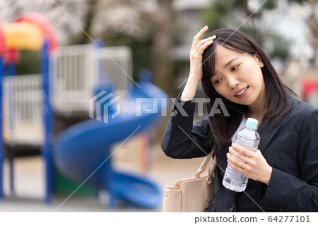Young woman with plastic bottle in park 64277101