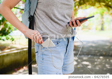 Female tourist connect smartphone to power bank 64278505