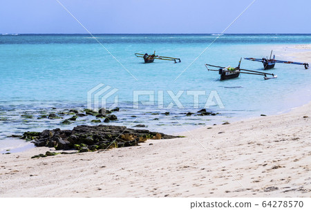 Stunning white sand beach of Nosy Ve island with typical outrigger pirogues moored in the background, Indian Ocean, Madagascar Stunning white sand beach of Nosy Ve island with typical outrigger pirogues moored in the background, Indian Ocean, Madagascar 64278570
