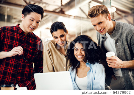 Cheerful young people using laptop at work 64279902