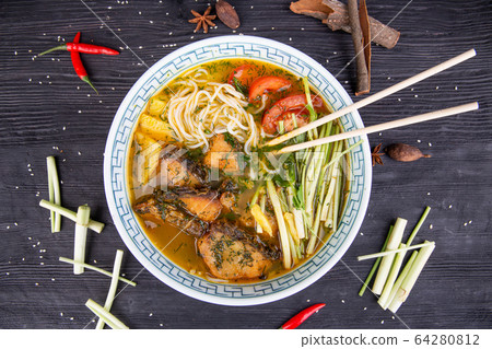 Wok soup with trout, tomatoes, onion feathers and chopped greens 64280812