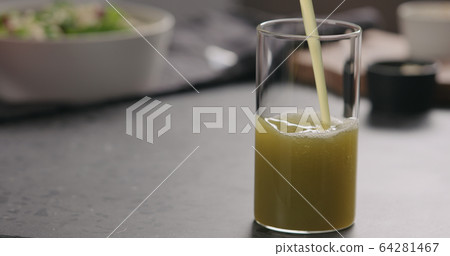 pour apple celery juice in glass on concrete countertop with copy space 64281467