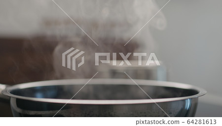 shot of steam rising from pan while cooking 64281613