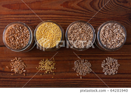 Cereal grains in glass jars on wooden background. Cereal grains in glass jars on wooden background. 64281940