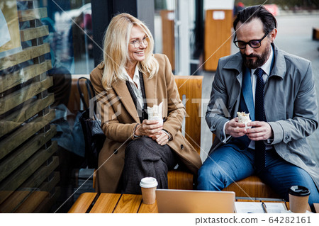Two Caucasian business people eating burritos outdoors 64282161