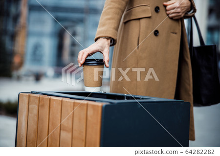 Female standing near a garbage can outdoors Female standing near a garbage can outdoors 64282282